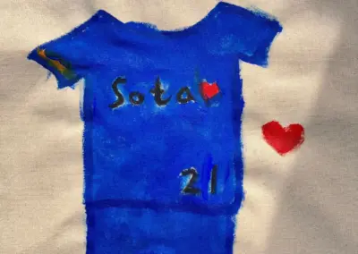 Blaue T-Shirt-Malerei mit dem Schriftzug 'Sota' und einer roten Herzzeichnung.
