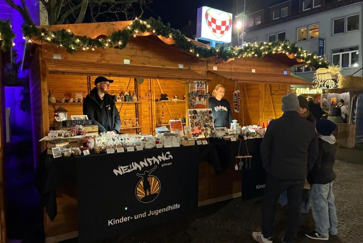 Zwei Verkaufsstände auf einem Weihnachtsmarkt mit handgefertigten Produkten und dekorativen Lichtern. Stände repräsentieren die Organisation Neuanfang Hamm.
