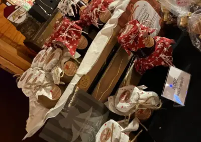 Geschenkpäckchen mit weihnachtlicher Dekoration auf einem Tisch, umgeben von weiteren Produkten und einem QR-Code.