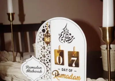 Dekoratives Ramadan-Kalender-Display mit goldenen Zahlen für den 7. Tag und arabischer Schrift, umgeben von Kerzen und Tischdekoration.