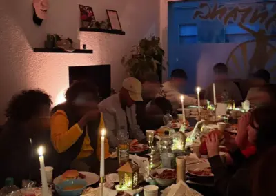 Tisch gedeckt mit Speisen und Getränken bei einer Feier, Kerzenlicht sorgt für eine gemütliche Atmosphäre.