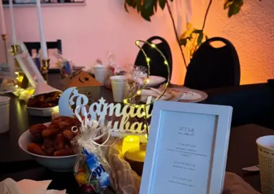 Tischdekoration mit einem Menürahmen, Snacks in einer Schüssel und dekorativen Lichtern in einem festlichen Raum.