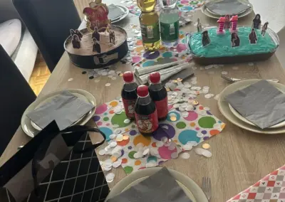 Bunter Tisch zum Kindergeburtstag mit Kuchen, Limonade, Konfetti, Servietten und Figuren-Dekoration; bereit für eine fröhliche Feier mit Familie und Freunden.