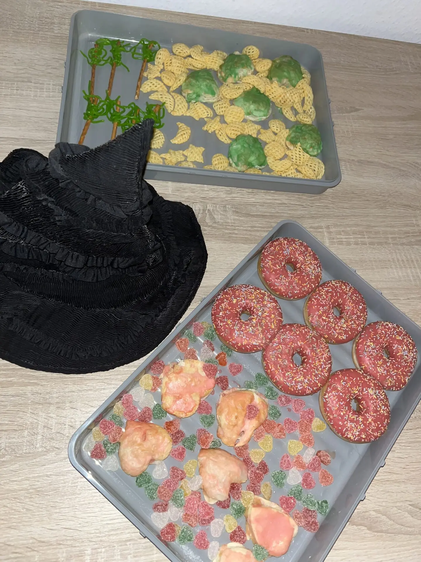 Feidikstraße WG Übernachtungsparty: bunte Snack-Tray mit rosa Donuts, grüne Kekse, farbige Gummibonbons, schwarzer Stoff, warme Atmosphäre – Momentaufnahme aus der WG